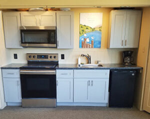 Looking toward the small kitchenette showing a range/oven, microwave, sink, small refrigerator, and coffeemaker